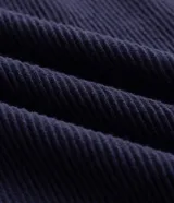 Remera de tejido texturizado color azul marino, con cuello redondo y mangas cortas con puños a rayas blancas. Presenta bordados frontales con la inscripción 'Future Co.', el número '98', un logo ovalado y estrellas.