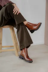 Bota corta de cuero marrón con panel trasero de gamuza en tono más oscuro, suela de goma negra y taco cuadrado bajo.