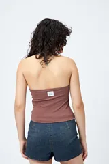 Top halter color marrón, con escote redondeado y detalle de ojales metálicos a lo largo del cuello. Presenta un diseño ajustado al cuerpo y espalda descubierta.