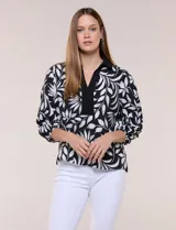 Blusa de calce suelto y caída ligera en color negro con estampado floral blanco, cuello camisero con escote en V y pechera en contraste. Presenta mangas tres cuartos abullonadas con puños elásticos.