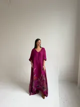 Vestido largo magenta con estampado floral en la parte inferior, de corte holgado y manga larga.