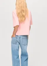 Jersey de punto color rosa, con cuello alto, manga corta y diseño recto.