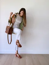 Cartera bandolera de cuero color tostado, con correa larga regulable, bolsillo frontal y forro de tela.