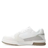 Championes urbanos de hombre, color blanco con detalles en beige claro y verde pálido. Presentan una silueta de corte bajo, cierre de cordones blancos y combinan texturas de cuero liso, gamuza y material sintético. La suela es gruesa, con entresuela blanca y parte inferior en tono marrón claro.