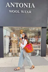 Cartera tipo tote bag confeccionada artesanalmente en cuero y gamuza, con diseño bicolor en verde y marrón. Presenta un detalle decorativo frontal con costuras a la vista en forma de abanico y flecos laterales. Es un modelo reversible con una cara lisa.