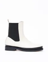 Bota Chelsea color hueso de cuero vacuno, con elástico lateral negro y suela de cuero.