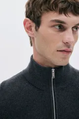 Sweater de punto acanalado color gris oscuro, con cuello alto y cierre frontal parcial metálico.