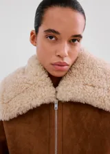 Chaqueta estilo aviador de ante sintético en color marrón con detalles de borrego sintético en el cuello, los puños, la solapa y el dobladillo inferior, con bolsillos laterales y cierre frontal con cremallera.