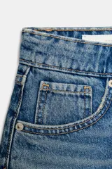 Shorts de denim azul claro lavado, tiro medio, corte en línea A y cinco bolsillos. Presenta cierre frontal con cremallera y botón metálico.