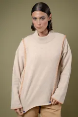Buzo de lana color beige con cuello redondo y costuras decorativas bordadas en color naranja a lo largo de los laterales y puños. Presenta un diseño holgado y mangas largas.