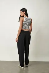 Pantalón negro de tiro alto y corte amplio, con pinzas en la cintura y bolsillos laterales.