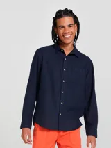 Camisa de manga larga en color gris, con cuello clásico, cierre frontal de botones y un bolsillo en el pecho.