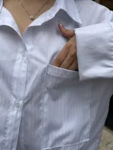 Camisa blanca de diseño oversize, con mangas largas, bolsillos frontales con solapa y cierre de botones.