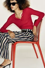 Pantalón de tiro alto y pernera recta con estampado de rayas verticales en tonos azul, marrón y beige. Incluye un cinturón delgado de color marrón oscuro con hebilla metálica dorada.