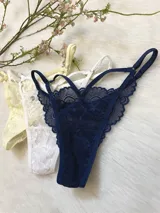 Pack de tres tangas de encaje con tiras regulables, colores variados: amarillo, blanco y azul marino.
