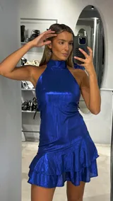 Vestido corto de fiesta color azul eléctrico, con cuello halter y falda con doble volado en el ruedo. Confeccionado en tejido brillante con textura.
