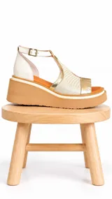 Sandalias de cuero con plataforma corrida, diseño combinado en tonos marfil, dorado y beige, con pulsera regulable al tobillo.