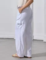 Pantalón de lino color blanco, de corte recto y tiro alto. Presenta bolsillos laterales tipo cargo y pretina elastizada en la parte trasera.