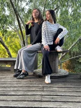 Remerón de manga larga, color blanco con rayas horizontales negras, corte oversize con tajos laterales y bajo redondeado.