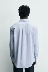 Camisa de corte regular fit confeccionada en tejido de algodón con diseño de rayas verticales finas. Presenta cuello abotonado, manga larga con puños abotonados, bolsillo plastrón en el pecho y cierre frontal con botones.