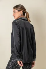 Camisa color crema de satén italiano con cuello clásico, cierre frontal con botones y mangas largas. Presenta apliques de strass en cuello, solapa y puños.