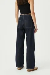 Pantalón jean azul oscuro de corte ancho, tiro medio, con bolsillos delanteros aplicados y costuras pespunteadas en contraste.