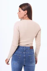 Remera de manga larga en tejido de punto acanalado, color blanco, con cuello redondo y cierre frontal parcial con botones.