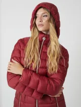 Campera de abrigo Michael Kors color bordó, con diseño acolchado, cierre metálico frontal y bolsillos delanteros. Incluye capucha desmontable y avíos metálicos con el logo de la marca.