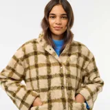 Chaqueta de tejido polar o efecto borreguito, color beige con estampado a cuadros en tono verde oliva. Presenta cuello alto con cierre de cremallera frontal.