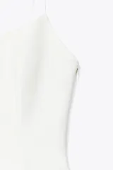 Top blanco de tejido elástico con escote redondo, tirantes finos y bajo con vuelo tipo peplum. Cierre lateral con cremallera oculta.
