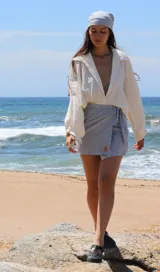 Conjunto compuesto por un pareo corto tipo falda cruzada con estampado de rayas verticales y una bandana a juego. El pareo cuenta con un lazo lateral para ajuste y un pequeño detalle bordado en el frente.