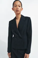 Blazer entallada de Zara, confeccionada en hilatura con lana. Presenta cuello solapa de muescas, manga larga con botones en puños, bolsillos de vivo en el delantero y cierre frontal cruzado con botones.