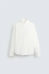 Camisa de algodón color blanco hueso, de corte regular, con cuello abotonado, manga larga terminada en puño con botón y bolsillo de parche en el pecho.