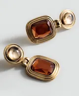 Aros colgantes dorados con diseño articulado, compuestos por una pieza circular superior con piedra semiesférica y una pieza rectangular inferior con piedra facetada color ámbar.