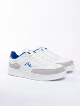 Championes urbanos blancos con detalles en gris, azul y rojo. Presentan el logo de la marca en el lateral y cordones blancos.