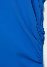 Vestido midi de fiesta color azul eléctrico, con cuello redondo y diseño sin mangas. Presenta un detalle drapeado lateral en la cintura y corte evasé fluido.