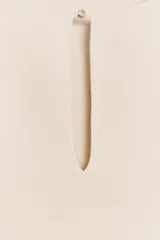 Top color crudo de tejido de punto con escote barco, manga sisa y abertura con abalorio en el centro.