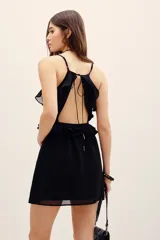 Vestido corto negro de viscosa georgette, con escote en V, breteles finos y volados decorativos en el frente.