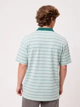 Chomba Rusty modelo Baviera de corte holgado, con diseño a rayas horizontales en tonos azul y beige. Cuenta con cuello mao, cierre frontal con botones y parche bordado con logo en el pecho.