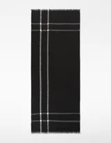 Chal rectangular de algodón orgánico y viscosa, color negro con diseño de cuadros escoceses en blanco. Presenta bordes deshilachados.