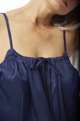 Musculosa de satén color negro, de corte holgado, con tirantes finos y escote fruncido ajustable con cordón.
