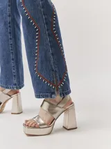 Sandalias de plataforma con taco cuadrado alto, confeccionadas en cuero metalizado color dorado. Presentan diseño de tiras anchas en el empeine y cierre con pulsera al tobillo.