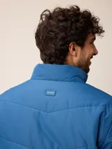 Campera acolchada de nylon color azul, con cierre frontal, cuello alto y logo de la marca bordado en el pecho.
