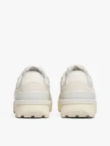 Zapatillas Tommy Jeans de estilo running, color blanco hueso, con exterior de ante, interior de poliéster y suela gruesa de goma con tacos. Presentan paneles con mezcla de texturas y detalles distintivos de la marca.