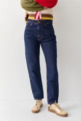 Jean de corte mom en color azul oscuro, con costuras en contraste de color rojizo y cierre frontal con botón metálico.