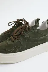 Zapatillas de gamuza verde oliva con cordones marrones y suela de goma color crema.
