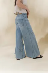 Pantalón de jean color beige, de tiro medio, corte amplio y ruedo acampanado.