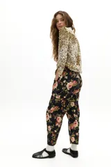 Pantalón de denim con corte barrel y tiro medio, estampado con diseño floral de rosas sobre fondo negro. Cuenta con pretina con pasacintos, bolsillos frontales, laterales y traseros, y largo hasta el tobillo.