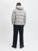 Campera puffer color gris claro, con capucha, cierre frontal con cremallera y diseño acolchado. Cuenta con puños internos acanalados y acabado resistente al agua.