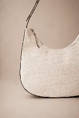 Cartera hobo de cuero color rojo con silueta curva de media luna, cierre superior y correa de hombro ajustable.